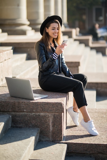 Young businesswoman student girl works with her brand laptop computer in the city centre