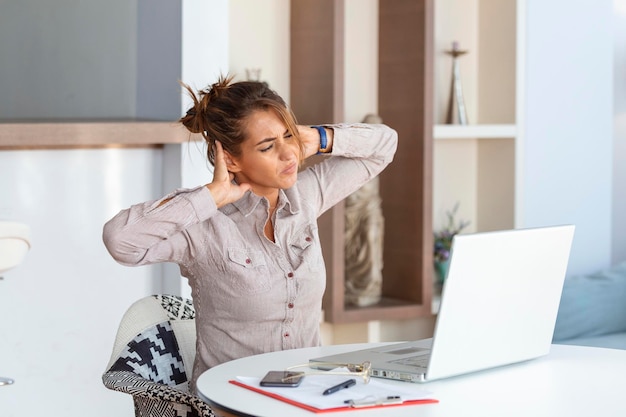 Young Businesswoman Suffering From Neckache Massaging her Neck While Sitting at Her Working Place in Home Office