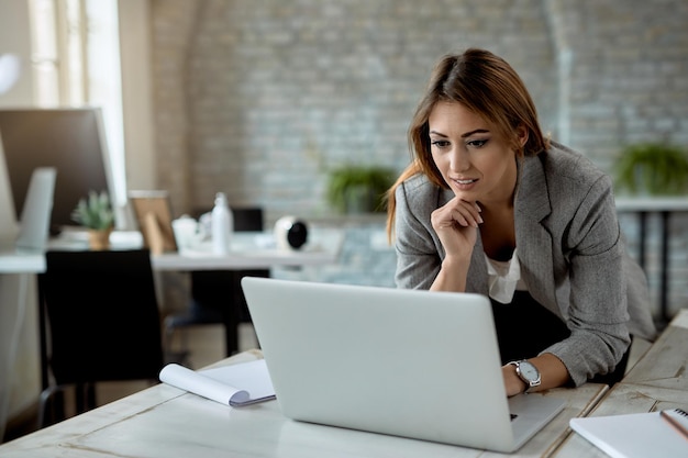 Young businesswoman surfing the net on a computer while working in the office