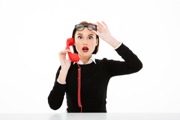 Free photo young businesswoman talking by phone surprised