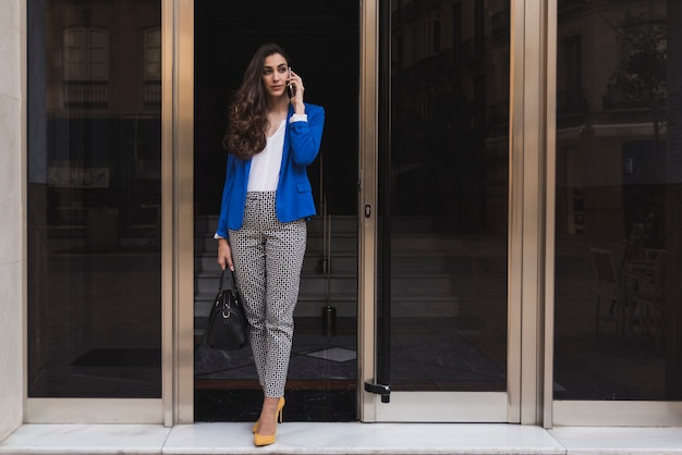 Free photo young businesswoman talking on the phone in the vestibule