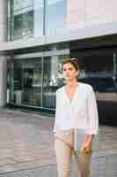 Free photo young businesswoman walking in front of corporate building