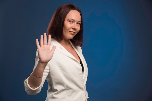 Young businesswoman in white blazer saying goodbye.