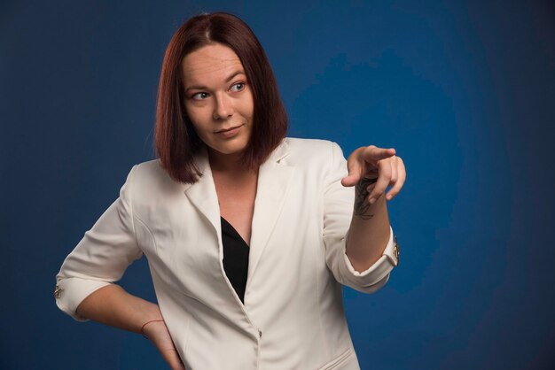 Young businesswoman in white blazer showing something. 