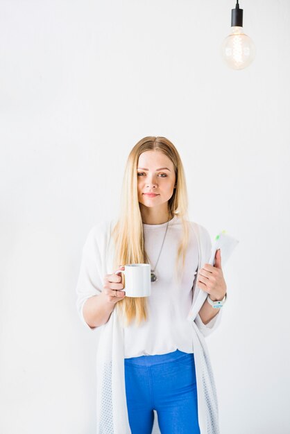 Young businesswoman with cup of tea looking at camera