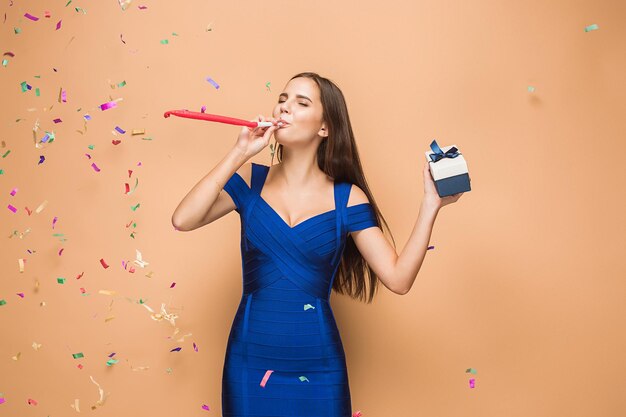 The young businesswoman with gift celebrating birthday, isolated on brown studio background