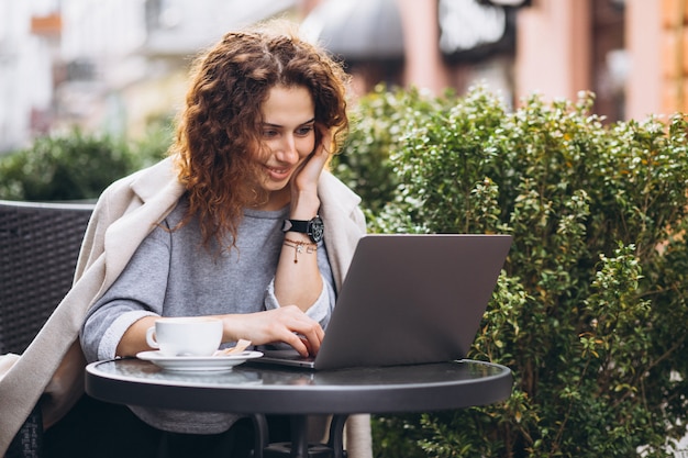 Giovane imprenditrice lavorando su un computer fuori dal bar