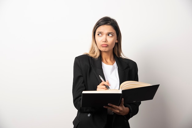 Young businesswoman writing in clipboard with pencil .