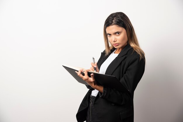 Young businesswoman writing in clipboard with pencil . 