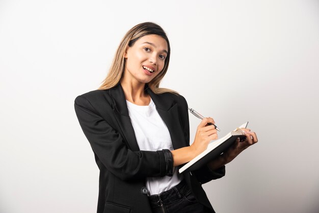 Young businesswoman writing in clipboard with pencil . 