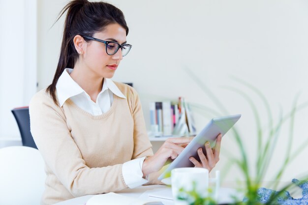 オフィスでデジタルタブレットを使用している若い経済婦人。