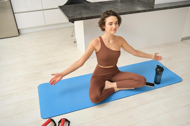 Free photo young calm fit healthy woman wearing sportswear sitting at home in living room doing yoga exercise m