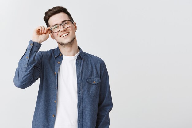Young carefree guy smiling, put on glasses