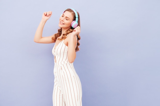 Young carefree model listening to music in wireless headphones