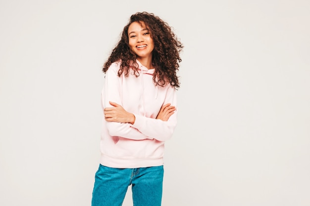 Young carefree woman posing on grey wall in studio