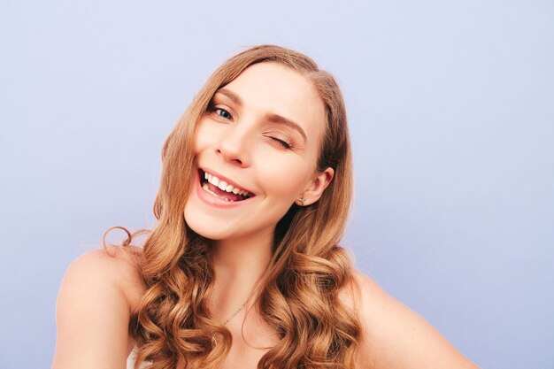 Young carefree woman posing near purple wall in studio