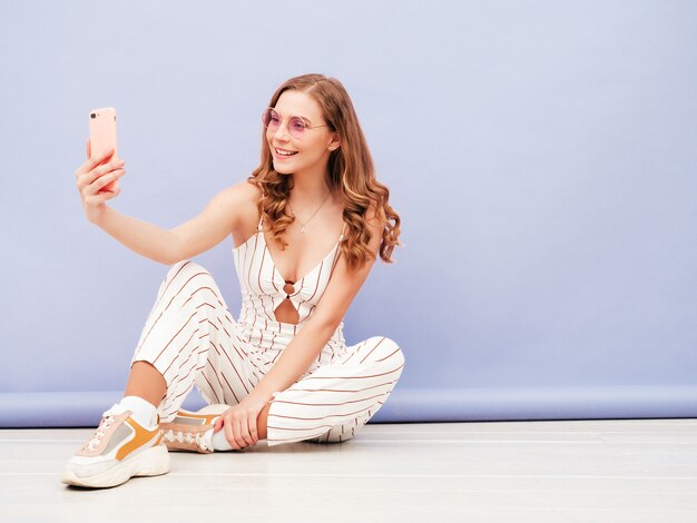 Young carefree woman posing near purple wall in studio