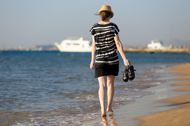 Young carefree woman walking through the surf