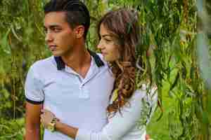 Free photo young casual couple enjoy of each other under green tree.