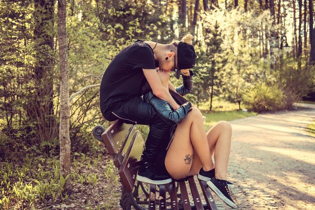 Молодая случайная пара отдыхает на скамейке в летнем лесу.