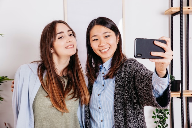 Foto gratuita giovani ragazze casuali che prendono selfie a casa