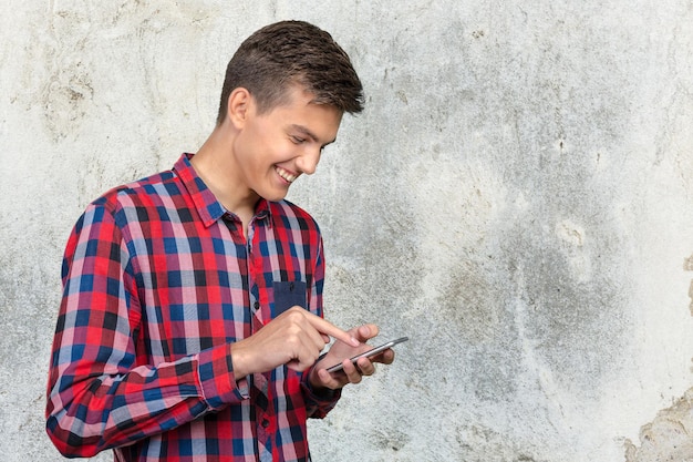 若いカジュアルな男性がスマートフォンにテキストメッセージを送信