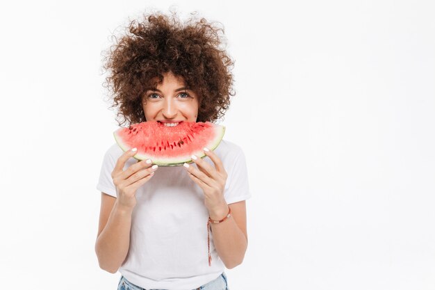 Young casual woman biting slice of a watermelon