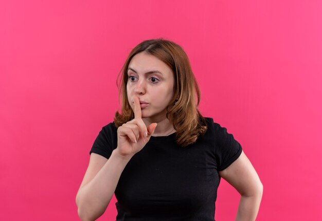 Young casual woman gesturing silence on isolated pink wall