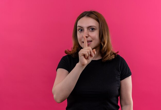 Young casual woman gesturing silence looking  on isolated pink wall with copy space