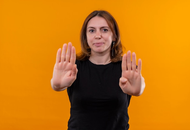 Giovane donna casuale che gesturing fermata e che osserva sulla parete arancione isolata con lo spazio della copia