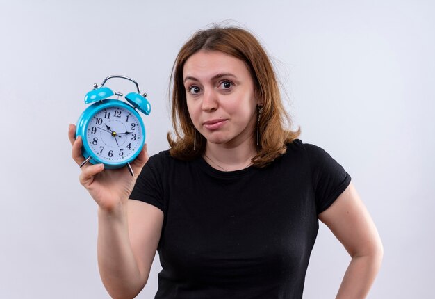 Young casual woman holding alarm clock looking  on isolated white wall