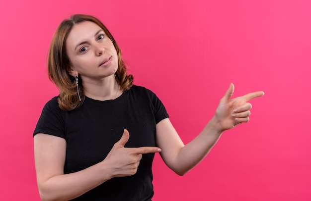 Young casual woman pointing at right side  on isolated pink wall