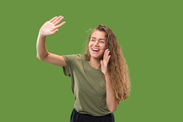 Young casual woman shouting. Shout. Crying emotional woman screaming on green studio background. Female half-length portrait.