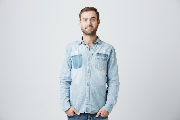 Young caucasian bearded man with hands in pockets