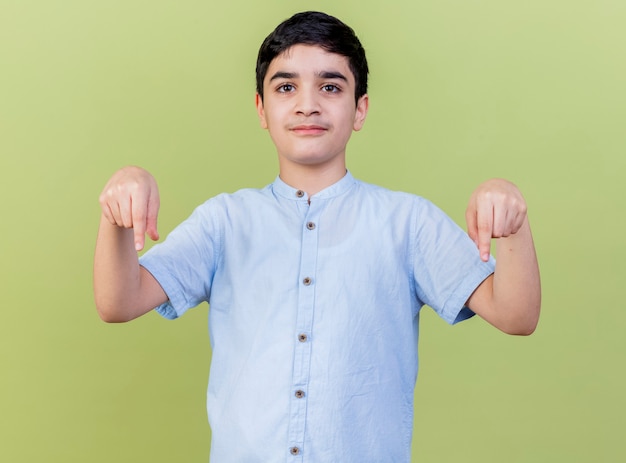 Free photo young caucasian boy  pointing down isolated on olive green wall