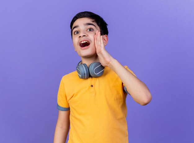 Young caucasian boy wearing headphones on neck isolated on purple background