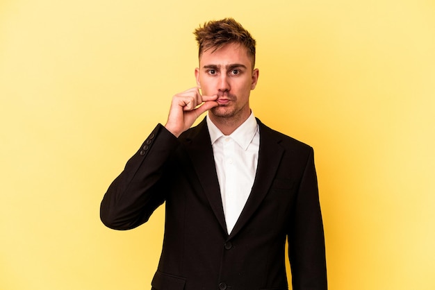 Young caucasian business man isolated on yellow background with fingers on lips keeping a secret. Premium Photo