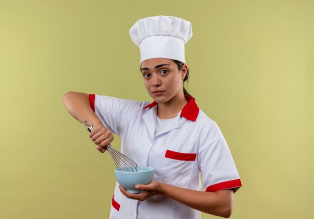 요리사 유니폼에 젊은 백인 요리사 소녀는 그릇을 보유하고 복사 공간이 녹색 배경에 고립 털