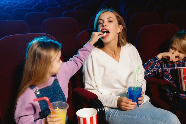 영화관, 집 또는 영화관에서 영화를보고 젊은 백인 가족. 표현력이 풍부하고 놀랍고 감정적으로 보입니다. 혼자 앉아서 즐겁게 지내기. 관계, 사랑, 가족, 어린 시절, 주말 시간.