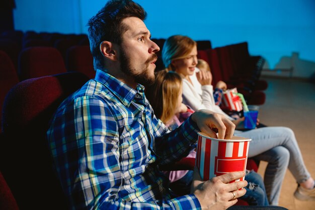 Young caucasian family watching a film at a movie theater, house or cinema.