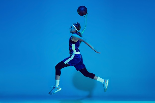 Young caucasian female basketball player  on blue neon light