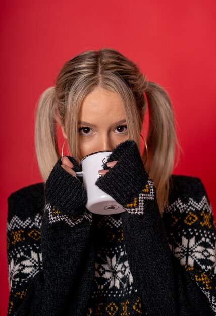 Young Caucasian female in a cute sweater drinking tea sitting