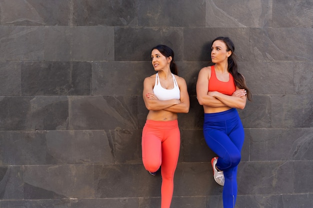 Young Caucasian female friends doing exercises and stretching outside - healthy lifestyle concept