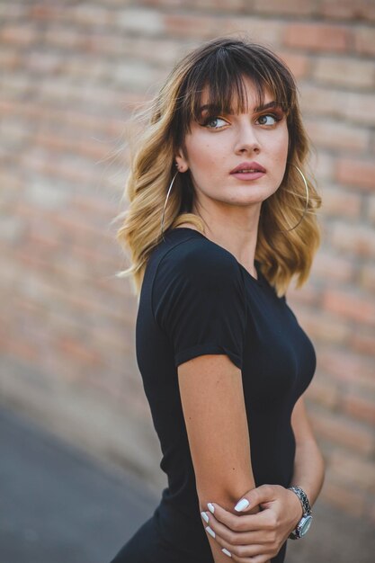 Young Caucasian female from Bosnia and Herzegovina in a black dress posing near a building