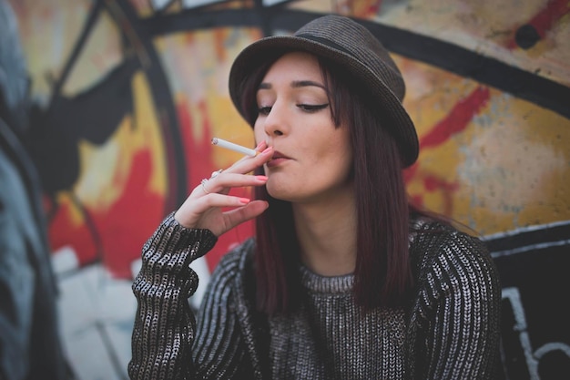 Young Caucasian female from Bosnia and Herzegovina in a shiny blouse smoking a cigarette