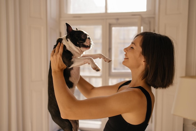 Young caucasian female owner playing with joyful black and white dog at home Play with pet concept