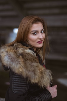 Giovane femmina caucasica con capelli castani che indossa un cappotto nero
