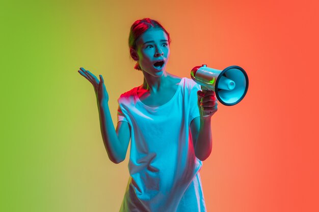 Young caucasian girl's portrait on gradient green-orange in neon light