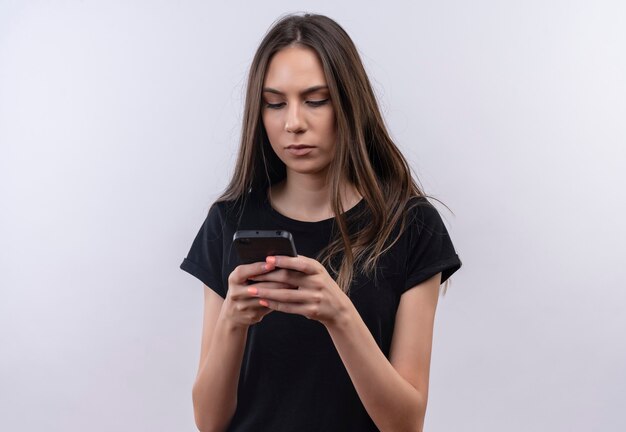 孤立した白の電話で黒のTシャツのダイヤル番号を身に着けている若い白人の女の子