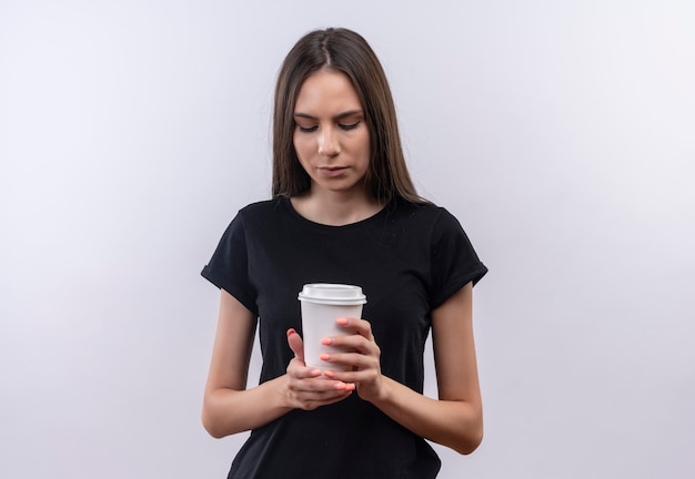 孤立した白で彼女の手にコーヒーのカップを見て黒いTシャツを着ている若い白人の女の子